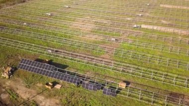 Yeşil alanda inşa halindeki güneş enerjisi santralinin havadan görüntüsü. Temiz ekolojik enerji üretmek için elektrik panellerinin montajı.