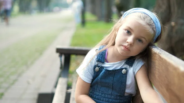 Klein Serieus Kind Meisje Zit Alleen Een Bank Zomer Park — Stockfoto