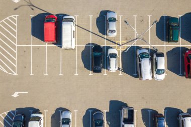 Otoparkta park yerleri ve yönler için çizgiler ve işaretlerle park edilmiş birçok renkli arabanın hava manzarası..