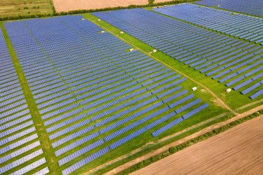 Temiz ekolojik elektrik enerjisi üretmek için birçok sıra güneş fotovoltaik paneli bulunan sürdürülebilir büyük elektrik santralinin havadan görünüşü. Sıfır emisyon kavramı ile yenilenebilir elektrik.
