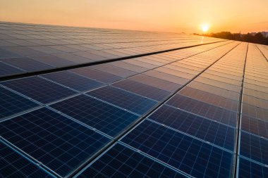 Mavi fotovoltaik güneş panelleri gün batımında temiz ekolojik elektrik üretmek için çatıya monte edildi. Yenilenebilir enerji konsepti üretimi.