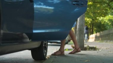 Şehir caddesinde yeşil bavulu arabadan çıkaran genç bir kadın sürücü. Seyahat ve tatil kavramı.