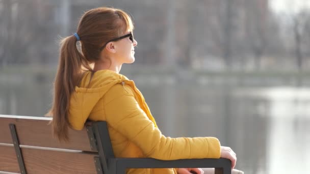 春天温暖的日子里 坐在公园长椅上休息的年轻女子 — 图库视频影像