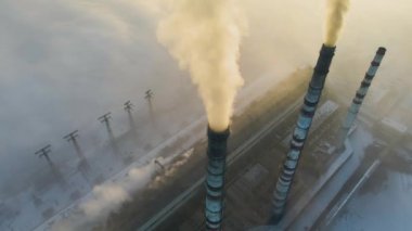 Kömür santralinin hava manzarası siyah dumanlı yüksek borular gün batımında atmosferi kirletiyor.
