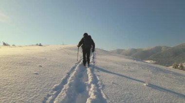 Soğuk kış gününde dağ yamacında yürüyüş yapan sırt çantalı adamın hava manzarası..