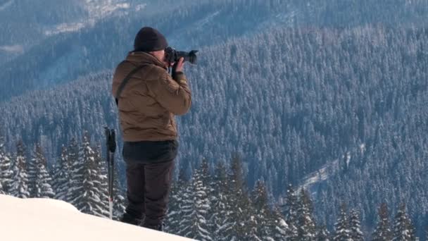 冬の山の中で雪の自然を撮影するハイカー写真家 — ストック動画