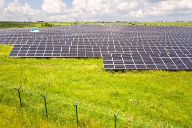 Yeşil alandaki güneş enerjisi santralinin koruyucu tel örgülü havadan görüntüsü. Temiz ekolojik enerji üretmek için elektrik panelleri.
