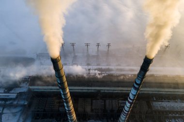 Kömür santralinin hava manzarası siyah dumanlı yüksek borular gün batımında atmosferi kirletiyor.