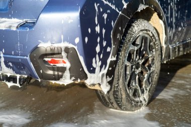 Erkek sürücünün otomobil yıkama servisinde yüksek basınçlı su jeti ile arabasını yıkaması..