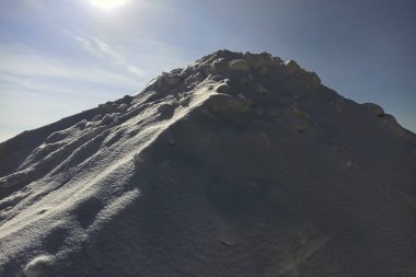 Kışın güneşli bir günde yüksek beyaz kar yığını.