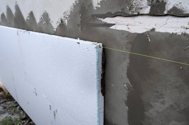 Termal koruma için ev cephesi duvarına köpük yalıtım çarşafları kurulumu.