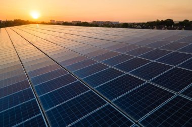 Mavi fotovoltaik güneş panelleri gün batımında temiz ekolojik elektrik üretmek için çatıya monte edildi. Yenilenebilir enerji konsepti üretimi.