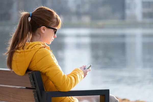 Молодая Красивая Женщина Сидящая Скамейке Парке Просматривает Свой Телефон Открытом — стоковое фото