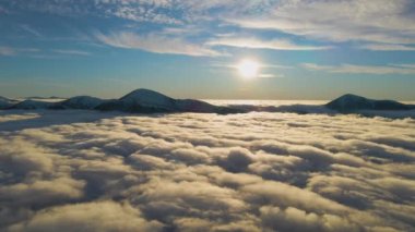 Ufuktaki Karpat dağlarının uzak karanlık zirveleriyle beyaz yoğun sis üzerinde canlı gün doğumunun havadan görüntüsü.
