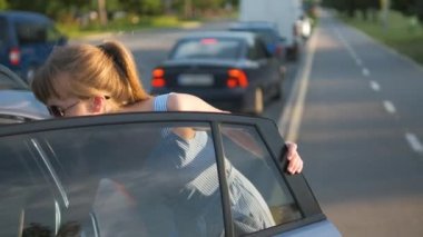 Şehir caddesinde yeşil bavulu arabadan çıkaran genç bir kadın sürücü. Seyahat ve tatil kavramı.