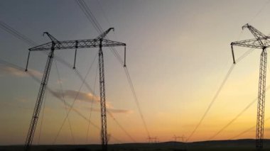 Gün batımında elektrik hatları olan yüksek voltaj kuleleri..