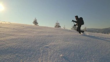 Sırt çantalı bir yürüyüşçü soğuk kış gününde karlı dağ yamacında yürüyor..