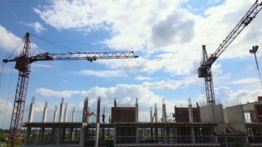 İnşaat halindeki yüksek beton binadaki vinç ve işçiler. Gayrimenkul geliştirme kavramı.