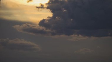 Gün batımında sarı gökyüzünde hızlı hareket eden bulutların hızlandırılmış görüntüleri.