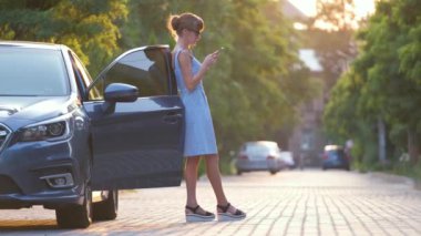 Sokakta yürürken yeşil bavulunu taşıyan genç bir kadın sürücü. Seyahat ve tatil kavramı.