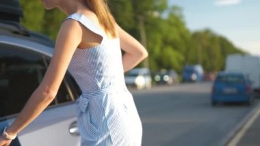 Arabasını sürmeye hazırlanmadan önce caddede yürüyen genç bir kadın sürücü..