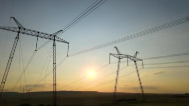 Gün batımında elektrik hatları olan yüksek voltaj kuleleri..