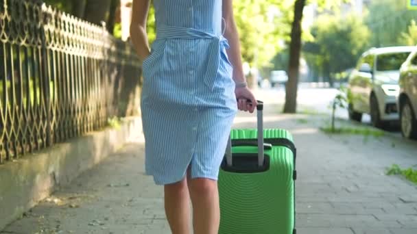 夏の日に緑のスーツケースと街の歩道を歩く若い女性の閉鎖 旅行と休暇のコンセプト — ストック動画