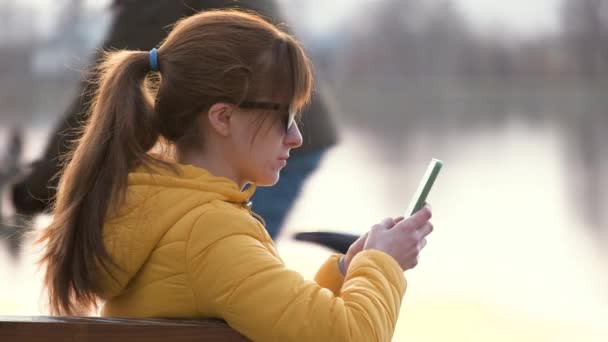 Jovem Mulher Bonita Sentada Banco Parque Navegando Seu Smartphone Livre — Vídeo de Stock