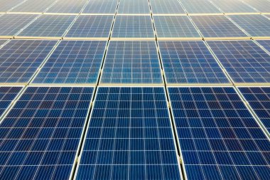 Temiz ekolojik elektrik üretmek için çatıya monte edilen mavi fotovoltaik güneş panellerinin havadan görünüşü. Yenilenebilir enerji konsepti üretimi.