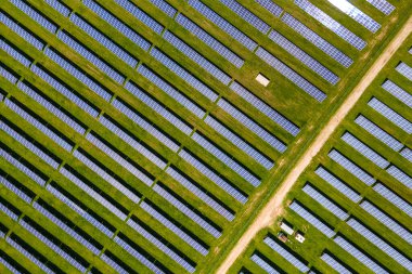 Temiz ekolojik elektrik enerjisi üretmek için birçok sıra güneş fotovoltaik paneli bulunan sürdürülebilir büyük elektrik santralinin havadan görünüşü. Sıfır emisyon kavramı ile yenilenebilir elektrik.