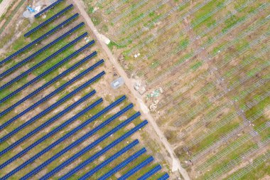 Metal çerçevesinde temiz ekolojik elektrik enerjisi üretmek için birçok sıra güneş paneli bulunan büyük elektrik santrali inşaatının havadan görüntüsü. Yenilenebilir elektrik kaynaklarının geliştirilmesi.