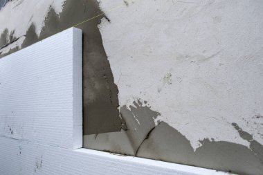 Termal koruma için ev cephesi duvarına köpük yalıtım çarşafları kurulumu.