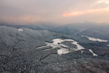 Soğuk ve sakin bir akşamda şiddetli kar yağışı sonrası dağ tepeleriyle kaplı kışın manzarası..