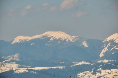 Soğuk kış günlerinde yoğun kar yağışı sonrası yüksek dağlık tepelerle kaplanmış kış manzarası..