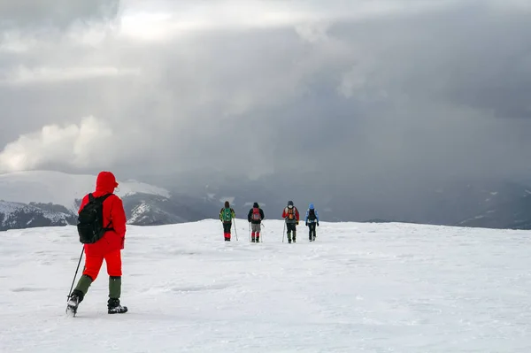 冬の山の中の雪に覆われた丘を歩くハイカーのバックビュー — ストック写真