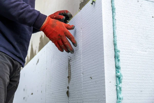 建筑工人在房屋正面墙壁上安装泡沫隔热板以进行保温 — 图库照片