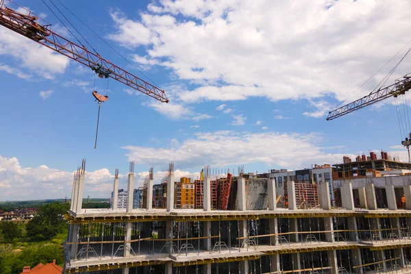 Tower crane at high concrete residential building under construction. Real estate development concept.