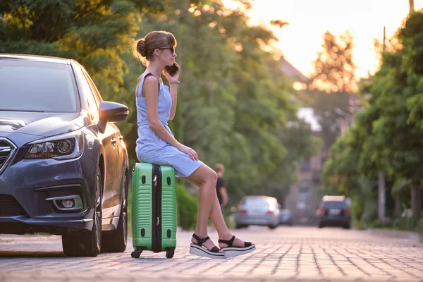 Junge Autofahrerin Sitzt Auf Koffer Neben Ihrem Auto Und Telefoniert — Stockfoto