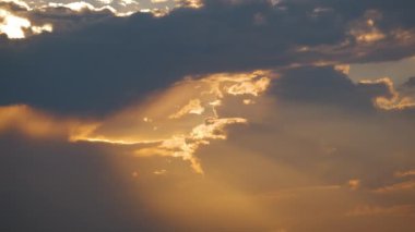 Günbatımında sarı gökyüzünde hızlı hareket eden akşam bulutlarının hızlandırılmış görüntüleri.
