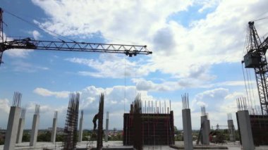 İnşaat halindeki yüksek beton binadaki vinç ve işçiler. Gayrimenkul geliştirme kavramı.