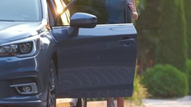 Sokakta yürürken yeşil bavulunu taşıyan genç bir kadın sürücü. Seyahat ve tatil kavramı.