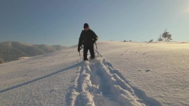 Buz gibi kış sabahında sırt çantalı bir adam dağ yamacında yürüyüş yapıyor..