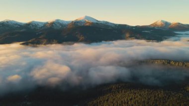Sonbaharda yeşil ladin ormanlarıyla kaplı dağ tepelerinin üzerinde canlı gündoğumunun hava manzarası..