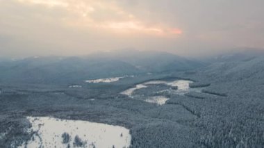 Soğuk ve sakin bir akşamda şiddetli kar yağışı sonrası dağ tepeleriyle kaplı kışın manzarası..