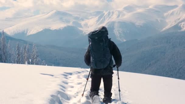 寒い冬の日に男バックパッカーのハイキング雪の山の中腹に — ストック動画