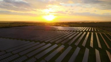 Günbatımında temiz ekolojik elektrik enerjisi üretmek için sıra sıra güneş fotovoltaik panelleri olan sürdürülebilir büyük elektrik santralinin havadan görünüşü. Sıfır emisyon kavramı ile yenilenebilir elektrik.