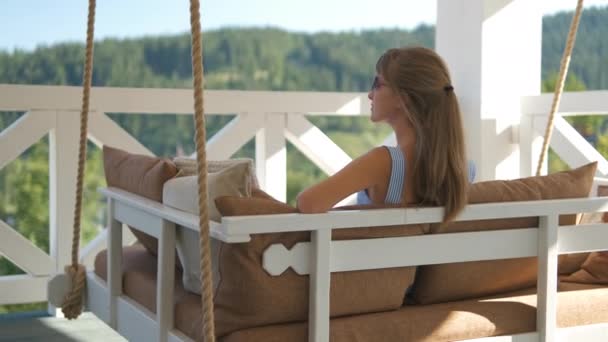 부드러운 베개가 테라스 소파에 풍경을 즐기는 갈색의 여자의 뒷모습 공기를 — 비디오