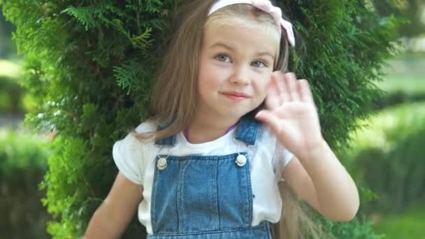 美しいです子供の女の子立って屋外で夏の公園手を振って — ストック動画