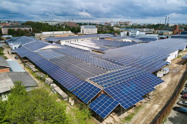 Sanayi binasının çatısına yeşil ekolojik elektrik üretmek için monte edilen mavi fotovoltaik güneş panellerinin hava görüntüsü. Sürdürülebilir enerji konsepti üretimi.