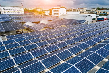 Sanayi binasının çatısına yeşil ekolojik elektrik üretmek için monte edilen mavi fotovoltaik güneş panellerinin hava görüntüsü. Sürdürülebilir enerji konsepti üretimi.